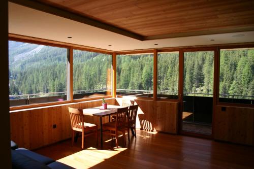 a dining room with a table and chairs and windows at Rumwaldhof - Wohnung Calendula in Solda