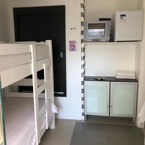 a room with a bunk bed and a desk with a microwave at Hotel Laçador in Santa Maria
