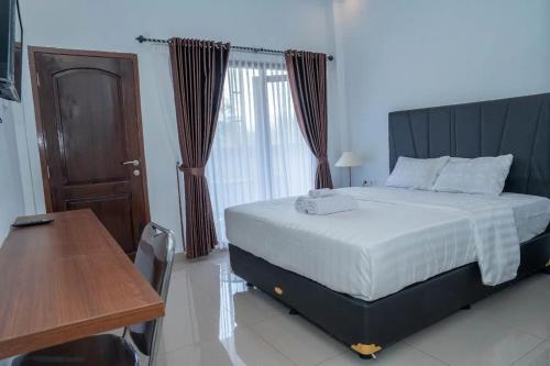 a bedroom with a large bed and a wooden desk at Fantasticroom Labuan Bajo in Labuan Bajo