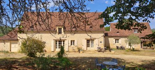 ein großes Backsteinhaus mit Tischen und Stühlen davor in der Unterkunft Terre de Jade in Savignac-de-Miremont