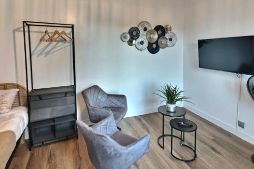 un salon avec deux chaises et une télévision dans l'établissement Oasis Urbaine, à Évreux