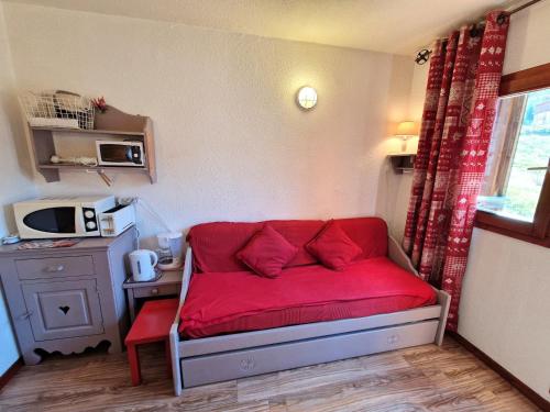 - un canapé rouge dans une pièce avec fenêtre dans l'établissement Charmant studio 2-3 pers avec balcon à Valfréjus - FR-1-265-214, à Valfréjus