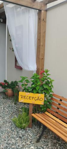 a wooden bench with a sign that says recede at Pousada Loft São Chico - Exclusiva para casais in São Francisco do Sul