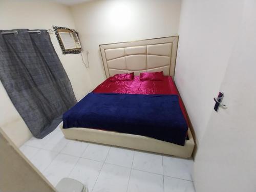 a small bedroom with a bed with a blue and red blanket at Room available in one bedroom appartment in Sharjah