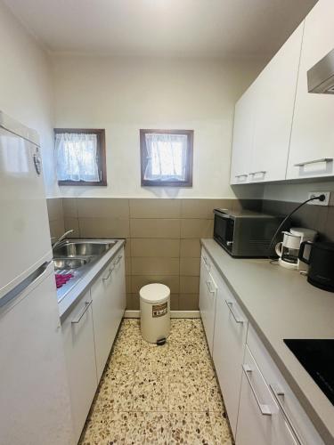 une cuisine avec des armoires blanches et un évier dans l'établissement Studio proche du centre-ville, à LʼÎle-Rousse