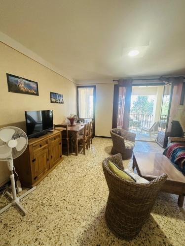 un salon avec une télévision, une table et des chaises dans l'établissement Studio proche du centre-ville, à LʼÎle-Rousse