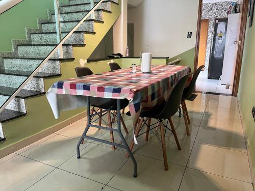 una sala da pranzo con tavolo, sedie e scale di Quartos na Praia - Cozinha Compartilhada, Self Check-in, WiFi, Próximo à Praia a Santos