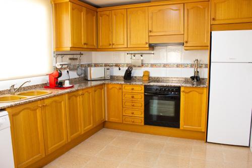 a kitchen with wooden cabinets and a white refrigerator at Casa Nuri de Rei La Pobla Tornesa in Puebla Tornesa