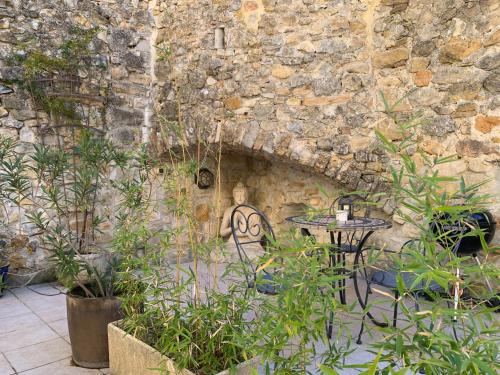 Una mesa y sillas frente a un muro de piedra. en LA PATISSERIE, en Saint-Sauveur-de-Cruzières