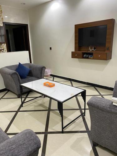 a living room with couches and a table and a tv at شقق راحتي جازان للشقق المخدومة in Jazan