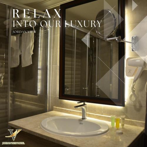 a bathroom with a sink and a large mirror at Jordan View Hotel in Amman