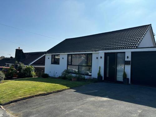 a white house with a garage and a driveway at Newly Refurbished Tor View Executive Dormer Bungalow Rossendale in Haslingden