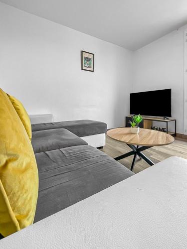 un salon avec un canapé et une télévision à écran plat dans l'établissement L'Échappée du Mans, au Mans