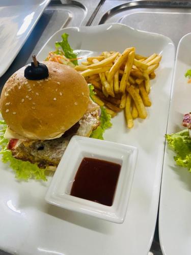 a white plate with a hamburger and french fries at Kamili Beach Resort, Kalutara in Kalutara