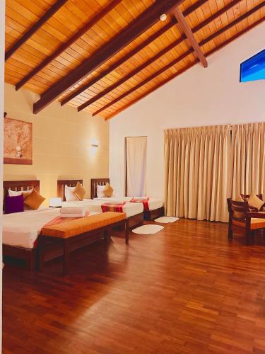 a large room with two beds and a wooden floor at Kamili Beach Resort, Kalutara in Kalutara