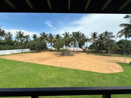 a large field with palm trees and the ocean at Kamili Beach Resort, Kalutara in Kalutara