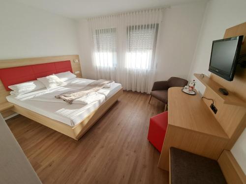 a small bedroom with a bed and a television at Hotel Rössle in Freiberg am Neckar
