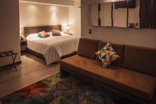 a hotel room with a bed and a couch at Hotel Platino Expo in Guadalajara