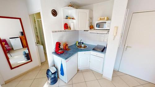 une petite cuisine avec un évier et un micro-ondes dans l'établissement T2 clim avec terrasse et place de parking privative, à Balaruc-les-Bains
