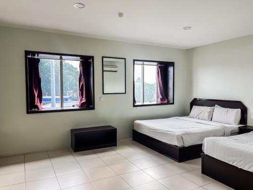 a bedroom with two beds and two windows at Ho Hotel in Melaka