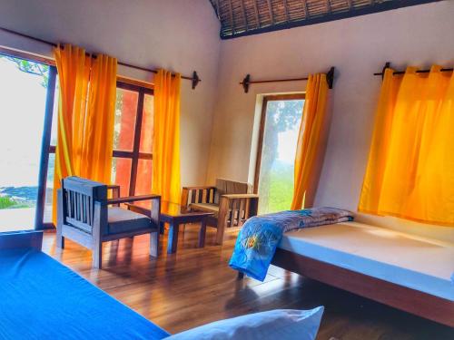 a bedroom with two beds and chairs and windows at Nosy-Borah Holidays in Analabe