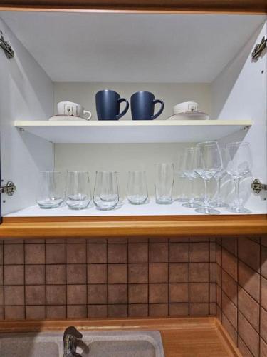 a shelf with wine glasses and cups on it at KT Apartment in Drama