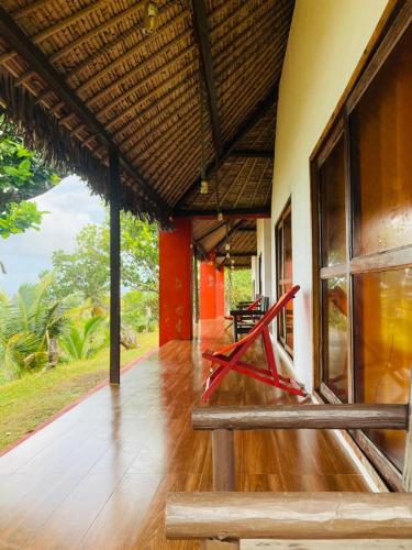 a porch of a house with a red bench at Nosy-Borah Holidays in Analabe