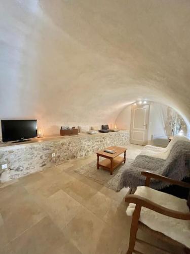 un salon avec une télévision et un mur en pierre dans l'établissement Maison provençale, à Bédoin