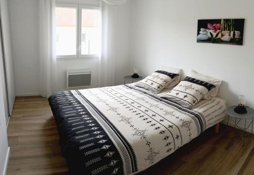 une chambre avec un lit avec une couverture noire et blanche dans l'établissement Maison Emeraude à Gan 64290, à Gan