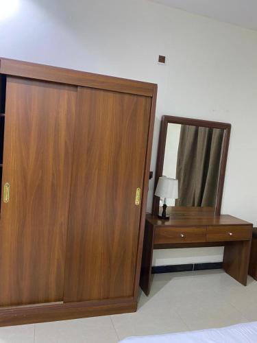 a bedroom with a wooden cabinet and a mirror at شقق راحتي جازان للشقق المخدومة in Jazan
