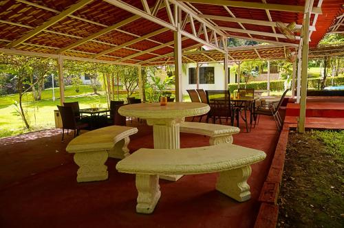 a patio with tables and chairs and a table and benches at Quinta Playa Blanca in Punta Leona