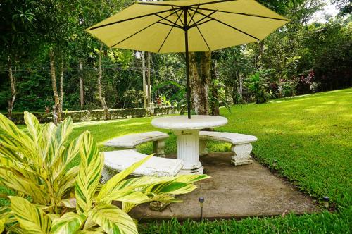 a table and benches with an umbrella in a yard at Quinta Playa Blanca in Punta Leona