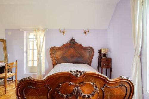 a wooden bed in a room with a window at La Maison d'Emma, 10 p, grand spa, 1 h15 de Paris in Venon