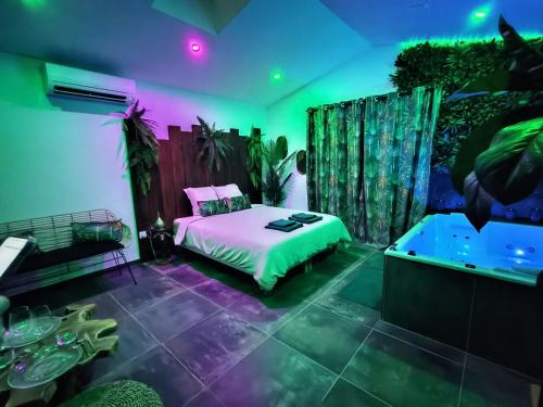 - une chambre avec un lit et une baignoire avec un éclairage violet et vert dans l'établissement La Jungle Room, à Rognac