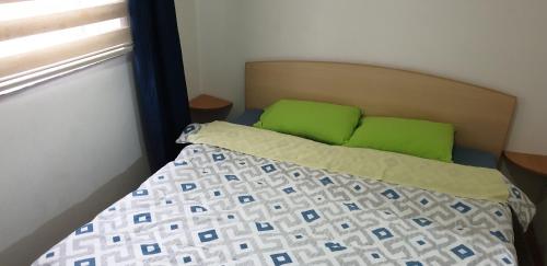 a bedroom with a bed with green pillows and a window at city center apartment 1 in Niš