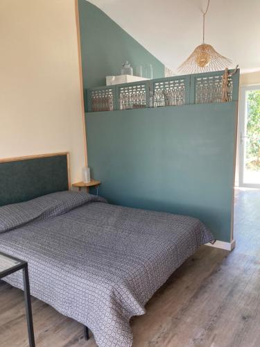 une chambre avec un lit et un mur bleu dans l'établissement Studio indépendant calme et climatisé en campagne, au Thor
