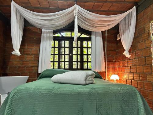 a bedroom with a green bed with a window at Pousada do Oasis in Morretes