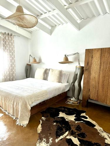 a bedroom with a bed and two lamps and a rug at Casa Vermelha in Praia do Tofo