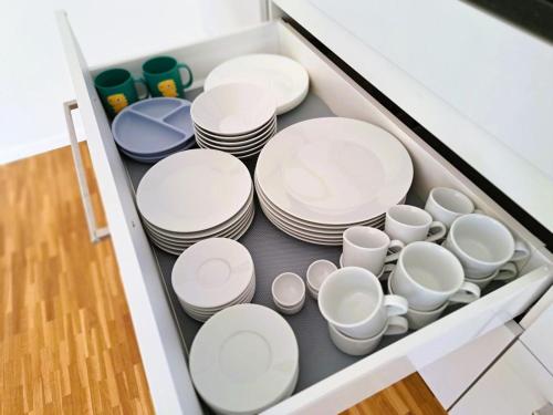 a drawer filled with white plates and cups at Business I Family Apartment I 1-4 Personen - Aare Blick, nahe Altstadt I Beamer - 99" Leinwand I Terrassen Lounge und Parkplatz in Brugg
