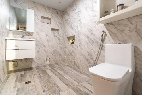 La salle de bains est pourvue de toilettes blanches et de murs en marbre. dans l'établissement Dolce Casa, à Juan Dolio