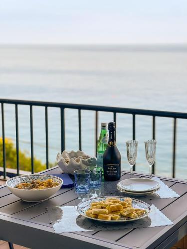 a table with plates of food and a bottle of wine at -Terrazza Sul Mare- & Parcheggio Privato in Varazze