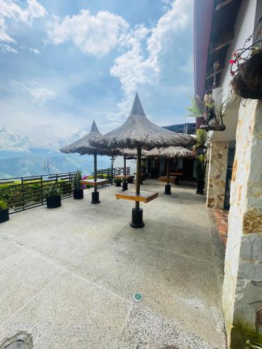 a patio with tables and umbrellas on top of a building at Entre Verdes Hotel & Glamping in Medellín