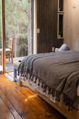 a bedroom with a bed and a large window at Tiny Cozy Cabin las moras in San Mateo Río Hondo