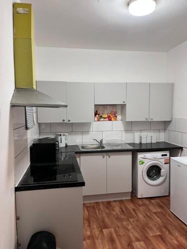 a kitchen with white cabinets and a washer and dryer at HIVESTAYS Free Wi-Fi, Smart TV, Parking, Tea &Coffee in Kettering