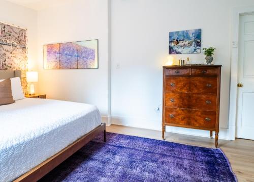 a bedroom with a bed and a dresser with a purple rug at Twin Gables of Woodstock in Woodstock