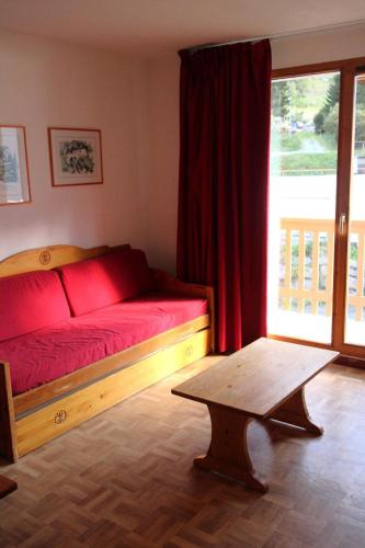 une chambre avec un lit rouge et une table en bois dans l'établissement Résidence Le Cheval Blanc - 3 pièces 6 personnes 37 m² MAE-2935, à Modane
