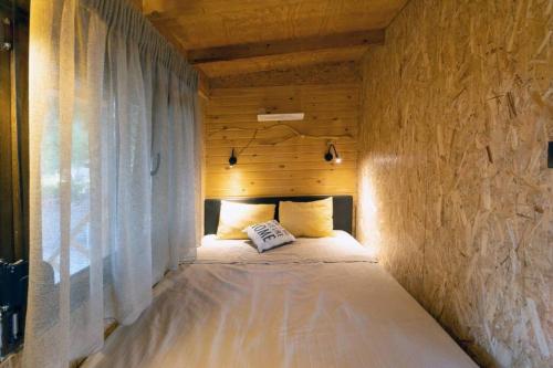 ein Bett in einem Zimmer mit einer Holzwand in der Unterkunft Sani Tree House in Sani Beach