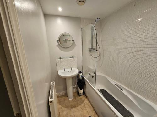 Un baño blanco con lavabo y ducha. en 2 bedroom spacious flat, en Gloucester