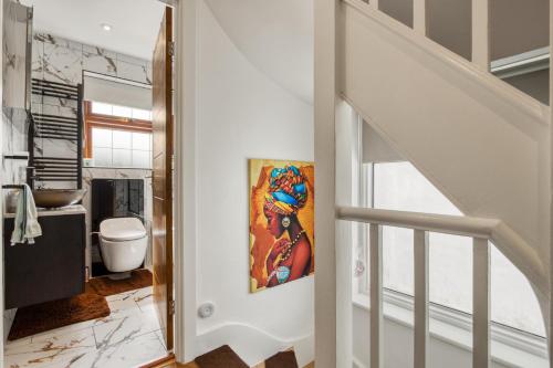 una escalera que conduce a un baño con una pintura en la pared en Casa Marina- 4 bedroom house with garden and balcony, en Golders Green