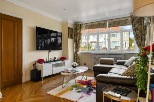 a living room with a couch and a tv at Casa Marina- 4 bedroom house with garden and balcony in Golders Green